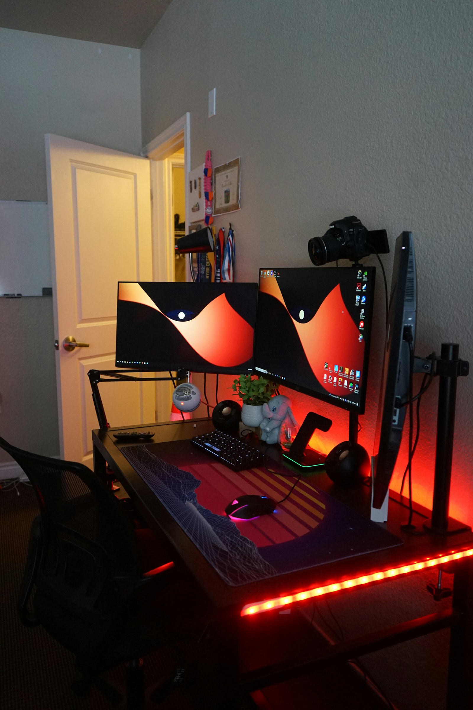 A red-lit desk with gaming monitors